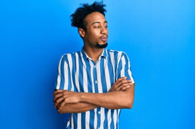 Sakallı, sıradan çizgili tişörtlü genç Afro-Amerikan bir adam. Gülümsüyor ve başka tarafa bakıyor.. 