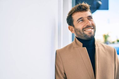 Zarif ceket giyen yakışıklı iş adamı dışarıda mutlu bir şekilde gülümsüyor.