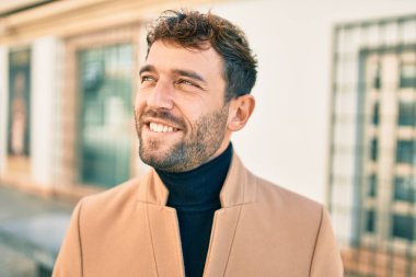 Zarif ceket giyen yakışıklı iş adamı dışarıda mutlu bir şekilde gülümsüyor.