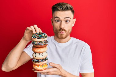 Genç kızıl saçlı adam elinde lezzetli renkli çöreklerle balık suratlı ve şaşı gözlü çılgın ve komik bakışlar atıyor.. 