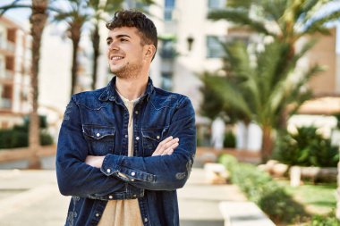 Genç İspanyol adam mutlu bir şekilde gülümsüyor şehirde çapraz hareketlerle