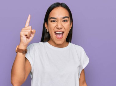 Sıradan beyaz tişört giyen Asyalı genç bir kadın başarılı bir fikri işaret ediyor. Heyecanlı ve mutlu. Bir numara.. 