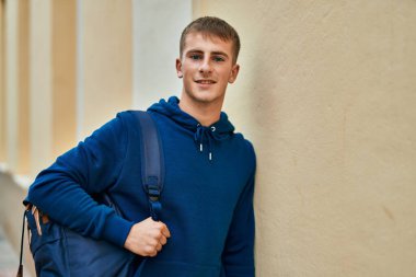 Üniversitede mutlu bir şekilde gülümseyen genç sarışın öğrenci..