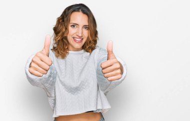 Güzel beyaz kadın, günlük kışlık süveter giyiyor. Elleriyle olumlu bir jest yapıyor. Gülümsüyor ve başarı için seviniyor. kazanan jest. 