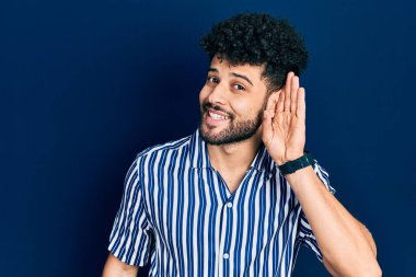 Sakallı, sıradan çizgili tişörtlü, ağzı kulaklarında, dedikoduları ve dedikoduları dinleyen genç bir Arap. Sağırlık kavramı. 