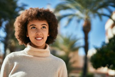 Genç İspanyol kız gülümseyerek şehirde mutlu mesut dikiliyor..