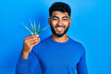 Sakallı bir Arap güvenlik kapısını açmak için maymuncuk tutuyor. Olumlu ve mutlu görünüyor. Kendine güvenen bir gülümsemeyle dişlerini gösteriyor. 