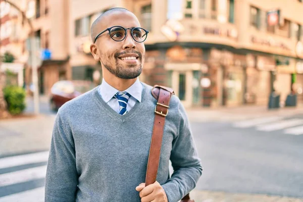 Genç Afrikalı Amerikalı iş adamı gülümseyerek şehirde mutlu bir şekilde yürüyor..