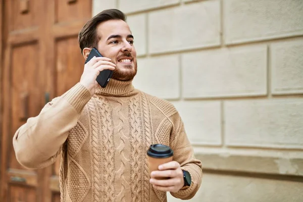 Kafkasyalı genç adam akıllı telefondan konuşuyor. Şehirde kahve içiyor..