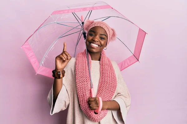 Mladá Afroameričanka Držící Deštník Překvapená Nápadem Nebo Otázkou Ukazující Prstem — Stock fotografie