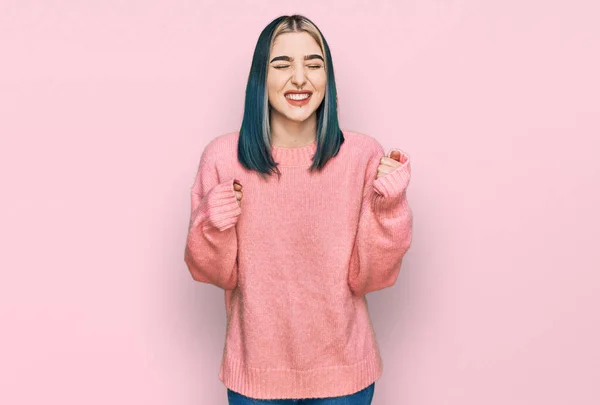 ピンクのウールの冬のセーターを身に着けている若い現代の女の子は腕を上げて成功のために興奮し 目は笑顔勝利を祝う閉じました 勝者のコンセプト — ストック写真