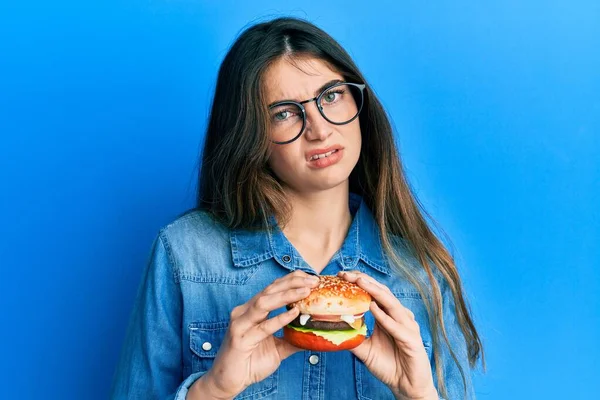 Fiatal Kaukázusi Eszik Egy Ízletes Klasszikus Burger Tudatlan Zavaros Kifejezés — Stock Fotó