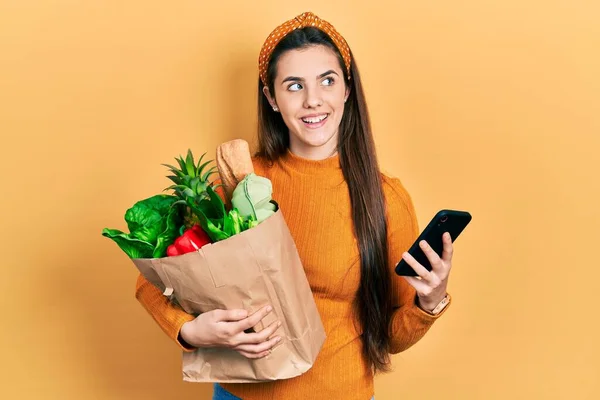 Ung Brunett Tonåring Håller Påse Med Livsmedel Med Smartphone Leende — Stockfoto