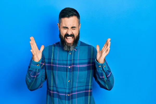 stock image Young hispanic man wearing casual clothes celebrating mad and crazy for success with arms raised and closed eyes screaming excited. winner concept 