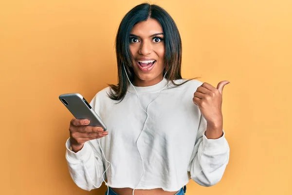 Młoda Latynoska Transseksualistka Używająca Smartfona Słuchawek Kciukiem Góry Uśmiechnięta Szczęśliwa — Zdjęcie stockowe