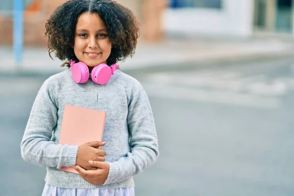 Adorável Estudante Hispânico Menina Segurando Livro Usando Fones Ouvido Cidade — Fotografia de Stock