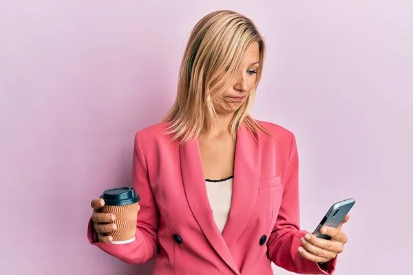 Piękna Blondynka Średnim Wieku Używa Smartfona Pije Filiżankę Kawy Depresji — Zdjęcie stockowe