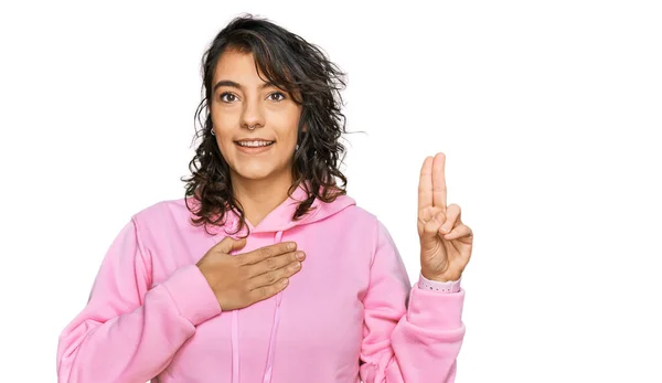 胸と指で手で身に着けて笑顔カジュアルスウェットを身に着けている若いヒスパニック系の女性 忠誠の誓いを作ります — ストック写真