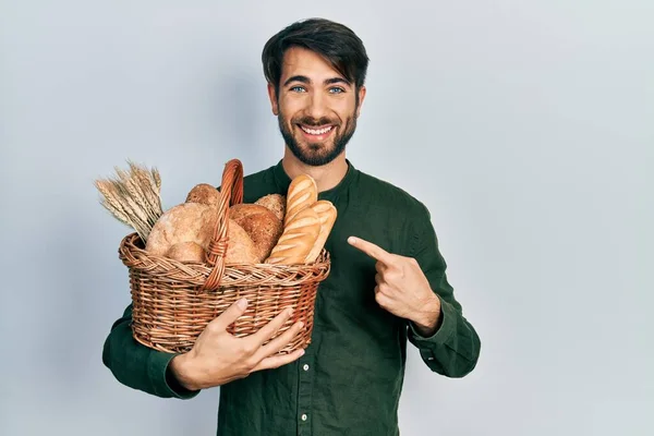 Молодий Іспаномовний Чоловік Тримає Плетений Кошик Хлібом Усміхненим Щасливим Вказівником — стокове фото
