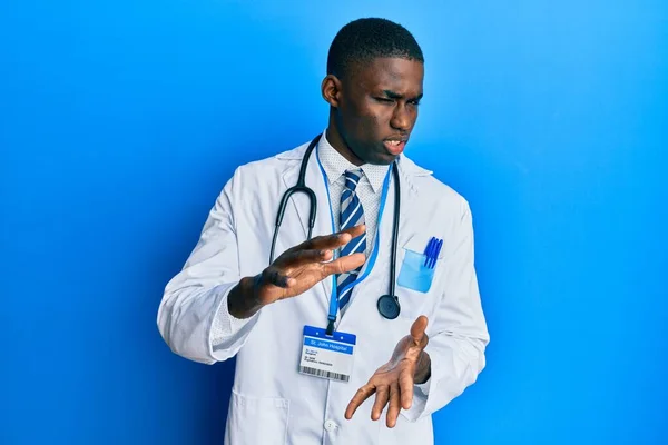 医者の制服を着た若いアフリカ系アメリカ人の男性は嫌悪反応のために嫌悪感の表情 不満と恐ろしい嫌悪感の顔をしている 手を挙げて — ストック写真