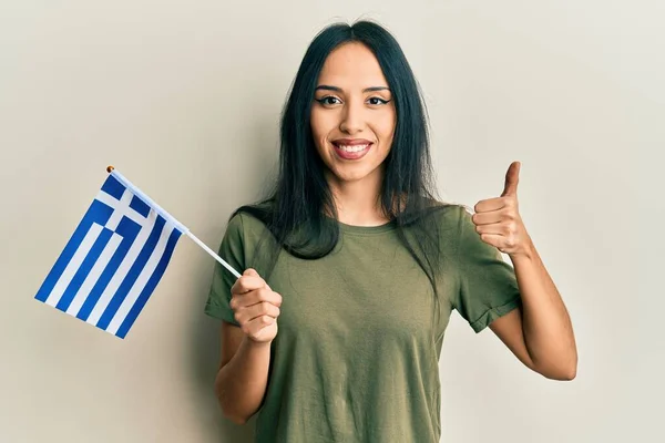 Młoda Latynoska Dziewczyna Trzyma Grecką Flagę Uśmiechnięta Szczęśliwy Pozytywny Kciuk — Zdjęcie stockowe