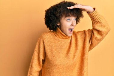 Kışın yün kazak giyen genç İspanyol kız çok mutlu ve gülümseyerek başını kaldırmış uzaklara bakıyor. arama kavramı. 