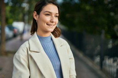 Genç İspanyol kadın gülümseyerek şehirde mutlu mesut dikiliyor.