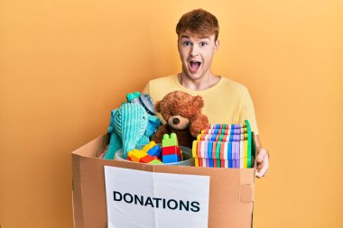 Kafkasyalı genç adam bağış kutusunu oyuncaklarla birlikte tutuyor. Çılgınca kutlama yapıyorlar ve başarıya hayret ediyorlar. Gözleri açık, heyecanla bağırıyorlar.. 