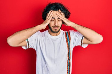 Yakışıklı, beyaz tişört giyen, baş ağrısı çeken çaresiz ve stresli bir İspanyol. Çünkü acı ve migren ağrısı var. Eller başının üstünde.. 