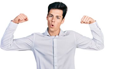 Genç İspanyol iş adamı iş kıyafetleri içinde gururla gülümseyen kol kaslarını gösteriyor. fitness konsepti. 