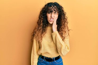 Günlük kıyafetler giyen genç İspanyol kız diş ağrısı ya da diş hastalığından dolayı acı dolu bir ifadeyle ağıza dokunuyor. dişçi 