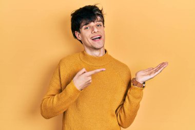 Yakışıklı hippi genç adam, gündelik sarı süveter giyiyor kameraya hayret ediyor ve gülümsüyor.. 