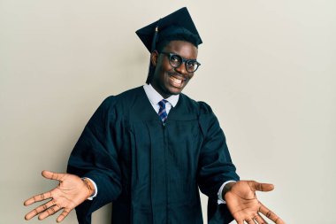 Mezuniyet şapkası ve tören cübbesi takan yakışıklı siyahi adam gülümsüyor, yardım eli uzatıyor ve kabul ediyor.. 