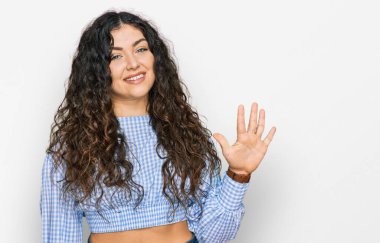 Gündelik kıyafetler giyen genç İspanyol kız beş numarayı gösterip işaret ederken kendinden emin ve mutlu gülümsüyor.. 