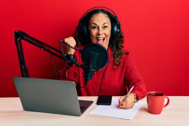 Güzel orta yaşlı kadın radyo stüdyosunda çalışıyor gururla bağırıyor, zaferi kutluyor ve kollarını kaldırarak çok heyecanlanıyor. 