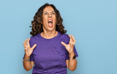 Orta yaşlı İspanyol kadın gündelik kıyafetler giyip deli gibi bağırıyor, agresif bir ifadeyle bağırıyor ve kollarını kaldırıyor. hüsran kavramı. 