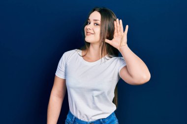 Günlük beyaz tişört giyen, ağzı kulaklarında gülümseyen genç İspanyol kız dedikoduları ve dedikoduları dinliyor. Sağırlık kavramı. 