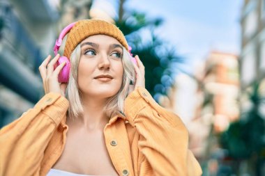 Şehirde kulaklık takan genç sarışın kız..