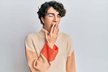 Günlük kışlık kazak giyen İspanyol genç adam ağzıyla ağzını kapatmaktan sıkılmış. Huzursuz ve uykulu.. 