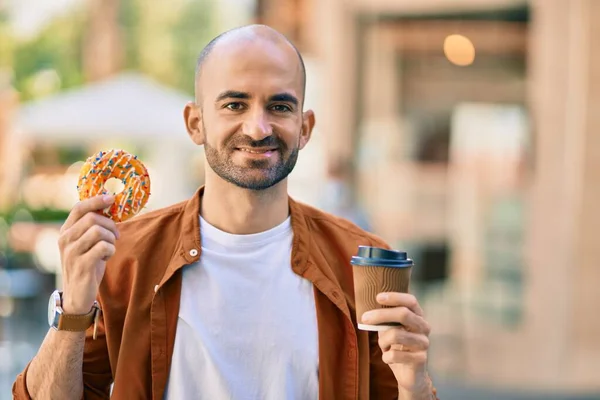 Young hispanic bald man smiling happy having breakfast at the city.