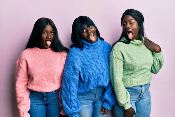 ウールの冬のセーターを着た3人の若いアフリカ系アメリカ人の友人が 面白い表情で舌を出している 感情の概念 — ストック写真