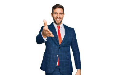 Sakallı, takım elbiseli ve kravatlı yakışıklı hoş geldin demek için gülümseyerek tokalaşıyor. başarılı iş. 