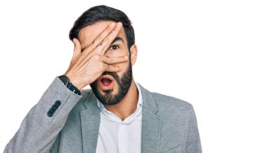 İş kıyafetleri giyen genç İspanyol adam şok içinde yüzünü ve gözlerini kapayarak utangaç bir ifadeyle parmaklarından bakıyor.. 