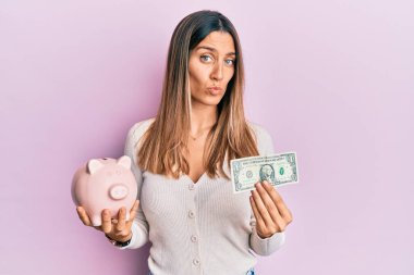 Kumral genç bir kadın elinde bir dolarlık banknot ve kumbarayla kameraya bakıyor. Öpüşme sahnesini çekiyor. Sevimli ve seksi. aşk ifadesi. 