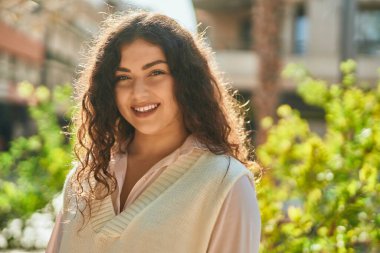 Genç İspanyol kadın gülümseyerek şehirde mutlu mesut dikiliyor..