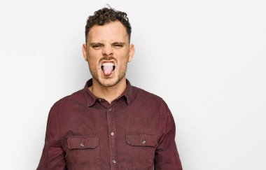 Günlük kıyafetler giyen genç İspanyol adam komik bir ifadeyle dilini dışarı çıkartıyor. duygu kavramı. 