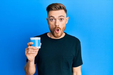 Kulak kiri temizleyici tutan genç kızıl saçlı adam korkmuş ve ağzı açık şaşkınlık içinde, inançsız yüz. 