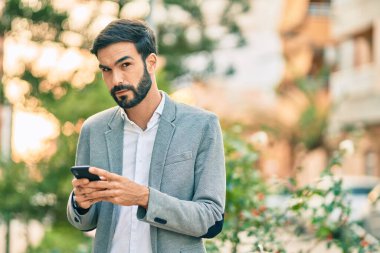 Şehirde akıllı telefon kullanan Latin asıllı genç bir işadamı..