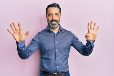 Orta yaşlı, sakallı, gri saçlı iş kıyafetleri giyen, dokuz numaralı parmaklarıyla işaret eden, kendinden emin ve mutlu bir adam.. 