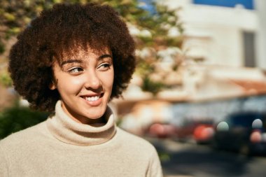 Genç İspanyol kız gülümseyerek şehirde mutlu mesut dikiliyor..